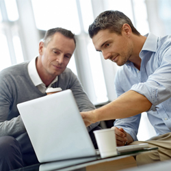 two men looking at a computer screen 