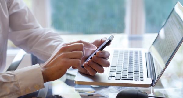 man at computer with cellphone 