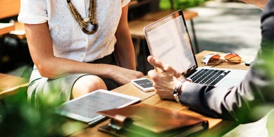 Two people sit at a table with a laptop open