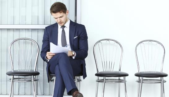 man sitting in chair looking over paper 